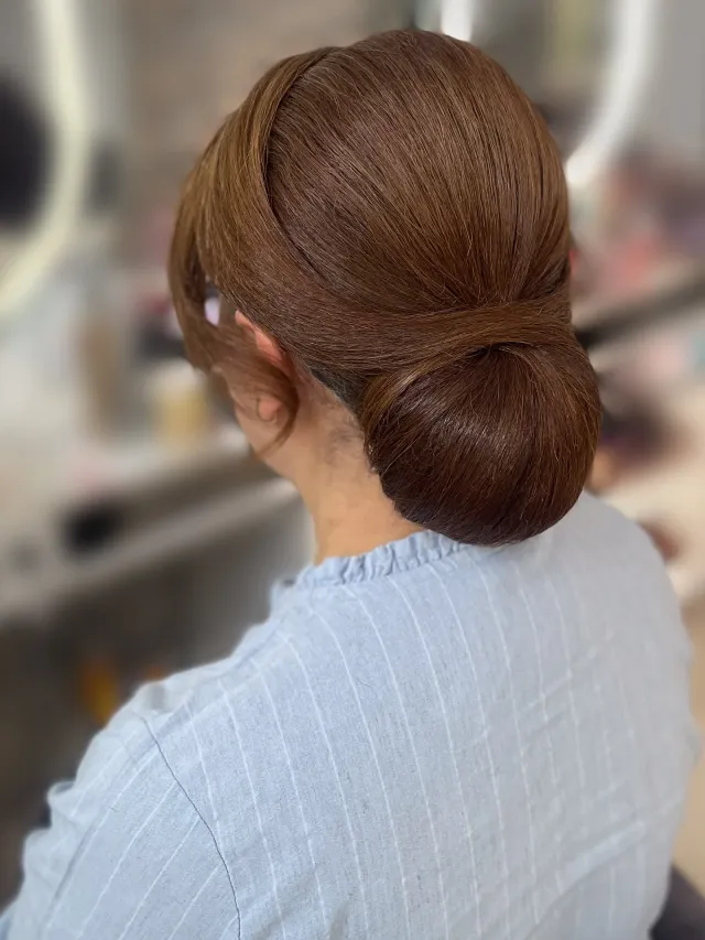 Elegante Hochsteckfrisur mit glattem Chignon und seitlich locker fallenden Strähnen, Rückansicht, Brautstyling Hamburg