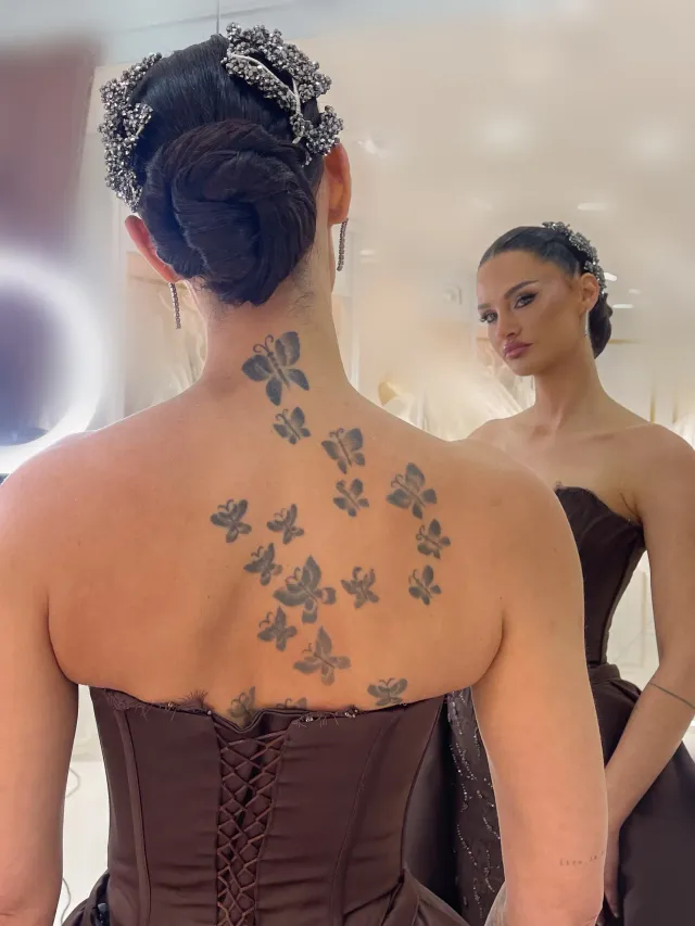 Elegante Hochsteckfrisur mit glattem Chignon und funkelnden Haarschmuck für Brautstyling in Hamburg, Rückenansicht mit Tattoos